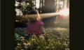 child in the woods staring at the sun